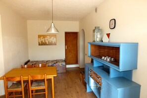 A dining area with a wooden table and chairs, a blue cabinet with drawers, a bench, and a painting on the wall.