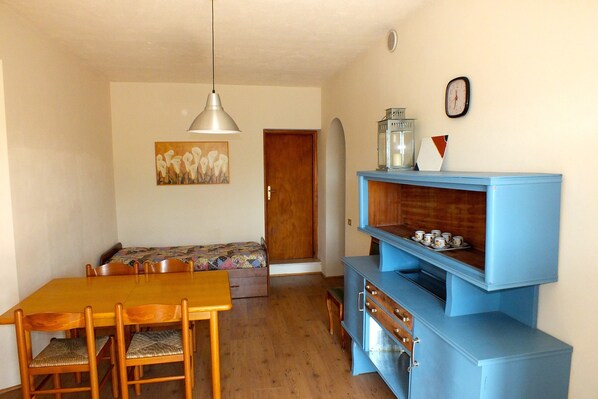 A dining area with a wooden table and chairs, a blue cabinet with drawers, a bench, and a painting on the wall.