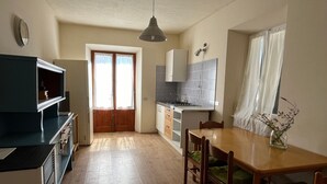 A compact kitchen with a dining area, wooden cabinets, a built-in stove, and a window with curtains.