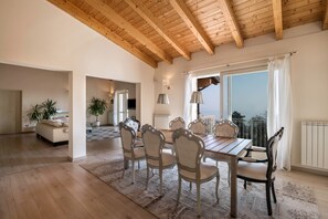 A spacious dining area with a wooden ceiling, large windows, and a view of the outdoors.