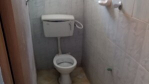 A small bathroom with a toilet, a sink, and a tiled floor. - Wanjambi Lodge (Nakuru)