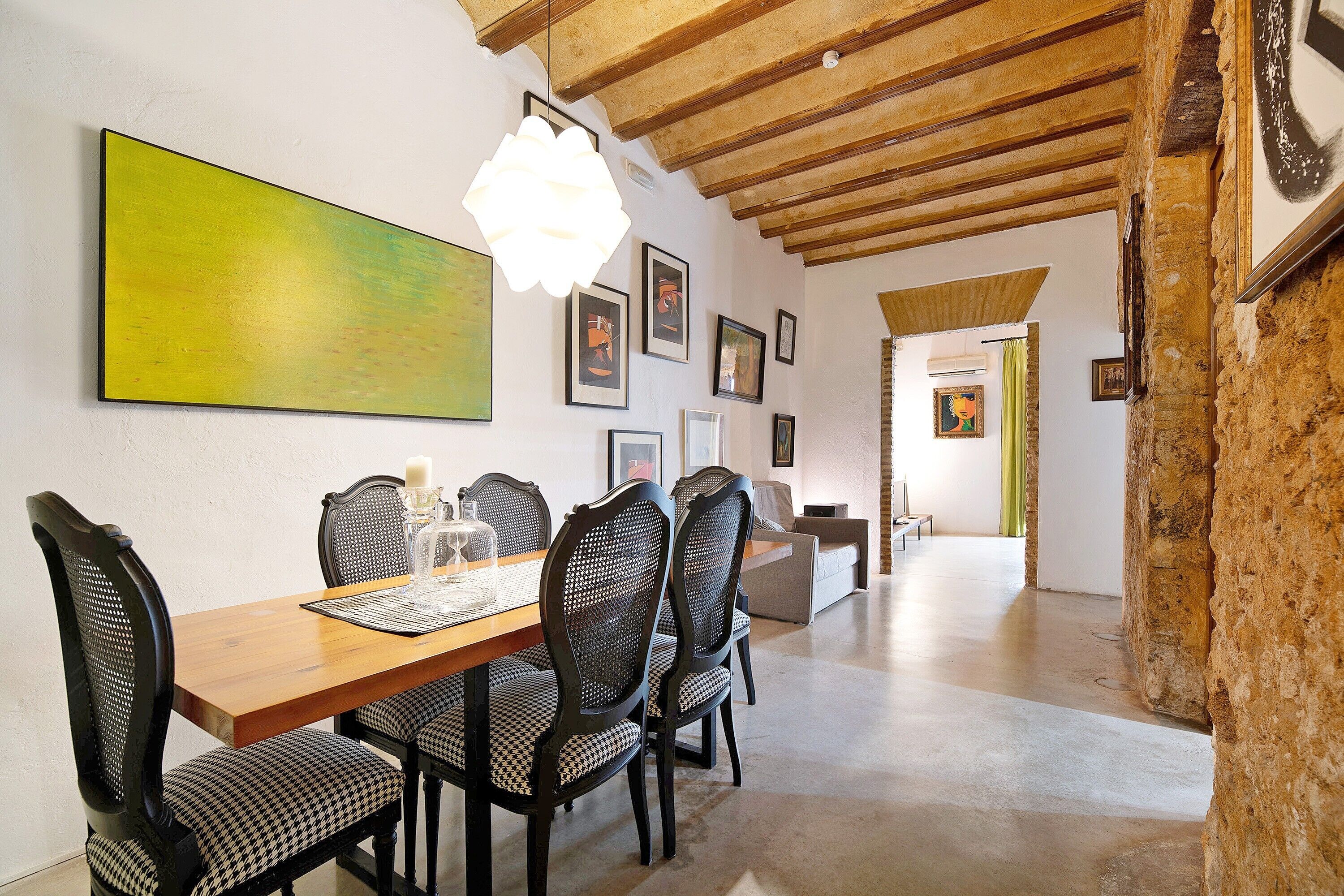 Een eethoek met een houten tafel en stoelen, een hanglamp en lijstwerken aan de wanden.