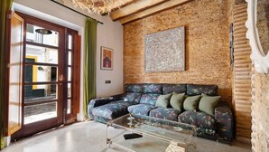 A room with a wooden ceiling, a glass coffee table, a patterned sofa, and a brick wall. - Historic and Modern Apartment with Air Conditioning and Wi-Fi (Cádiz)