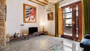 A living room with a TV, artwork, a bench, and a glass table. - Historic and Modern Apartment with Air Conditioning and Wi-Fi (Cádiz)