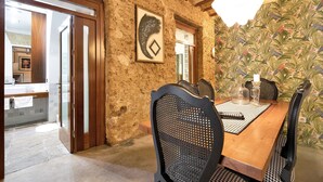 A dining area with a wooden table, black chairs, a hanging light fixture, and a mural on the wall. - Historic and Modern Apartment with Air Conditioning and Wi-Fi (Cádiz)