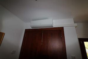 Una habitación con puerta de madera, techo blanco y un equipo de aire acondicionado sobre la puerta.