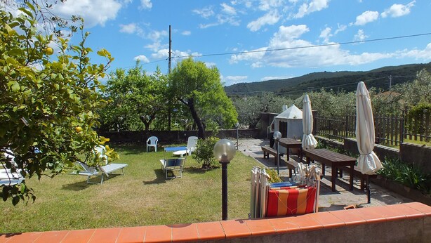 A backyard with a lawn, outdoor furniture, and a view of the countryside.