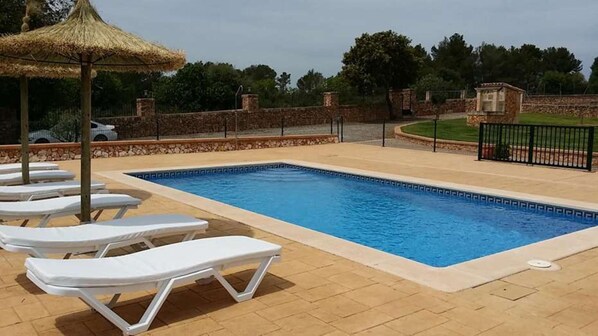 A swimming pool with lounge chairs and a thatched umbrella.