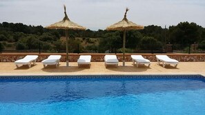 A swimming pool with lounge chairs and thatched umbrellas.