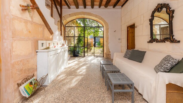 Ein gemütliches Interieur mit einem weißen Sofa, einer Holzbalkendecke und einem großen Bogenfenster.
