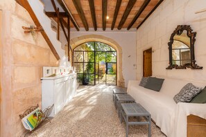 Un interior acogedor con un sofá blanco, techo de madera y un gran ventanal arqueado.