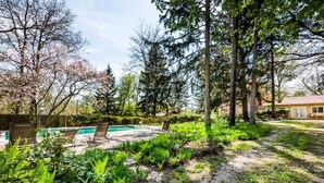 A backyard with a swimming pool, lounge chairs, and lush greenery. - UNION PIER HOME WITH PRIVATE HEATED POOL and BEACH ACCESS! (Lakeside)