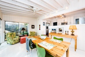 Een moderne keuken met witte kasten, een houten eettafel en een plafondventilator.