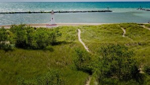 A lighthouse on a grassy beach with a clear view of the ocean. - UNION PIER HOME WITH PRIVATE HEATED POOL and BEACH ACCESS! (Lakeside)