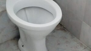 A white toilet in a bathroom with tiled walls and floor. - Wasafiri Guest House (Nakuru)
