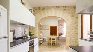 A kitchen with white cabinets, a dining table with chairs, and a stone archway. - Luxury town house with pool - Casa Pina (Pina)