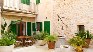 A courtyard with a wooden table and chairs, potted plants, and a stone wall. - Luxury town house with pool - Casa Pina (Pina)