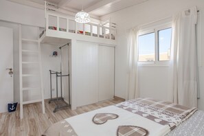 A bedroom with a bunk bed, a wardrobe, a shower, and a window with curtains.