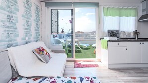 A modern interior with a sofa, a kitchen area, and a sliding glass door leading to an outdoor space. - Holiday Apartment "Atico Casapueblo" Near the Beach with Mountain View (Corralejo)