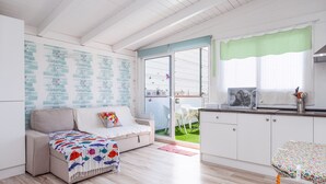 A cozy room with a sofa, a small table, a kitchen area, and a sliding glass door leading to an outdoor space. - Holiday Apartment "Atico Casapueblo" Near the Beach with Mountain View (Corralejo)