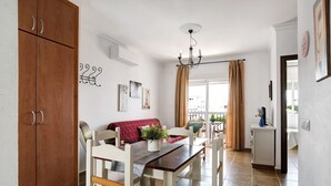 A dining area with a wooden table and chairs, a sofa, and a cabinet.