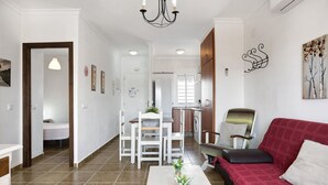 A living room with a red sofa, white coffee table, and a dining area with white chairs.
