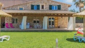 A stone house with a patio, outdoor seating, and a lawn. - In a Peaceful Location with Garden – Villa Can Ferrer (Alcudia)