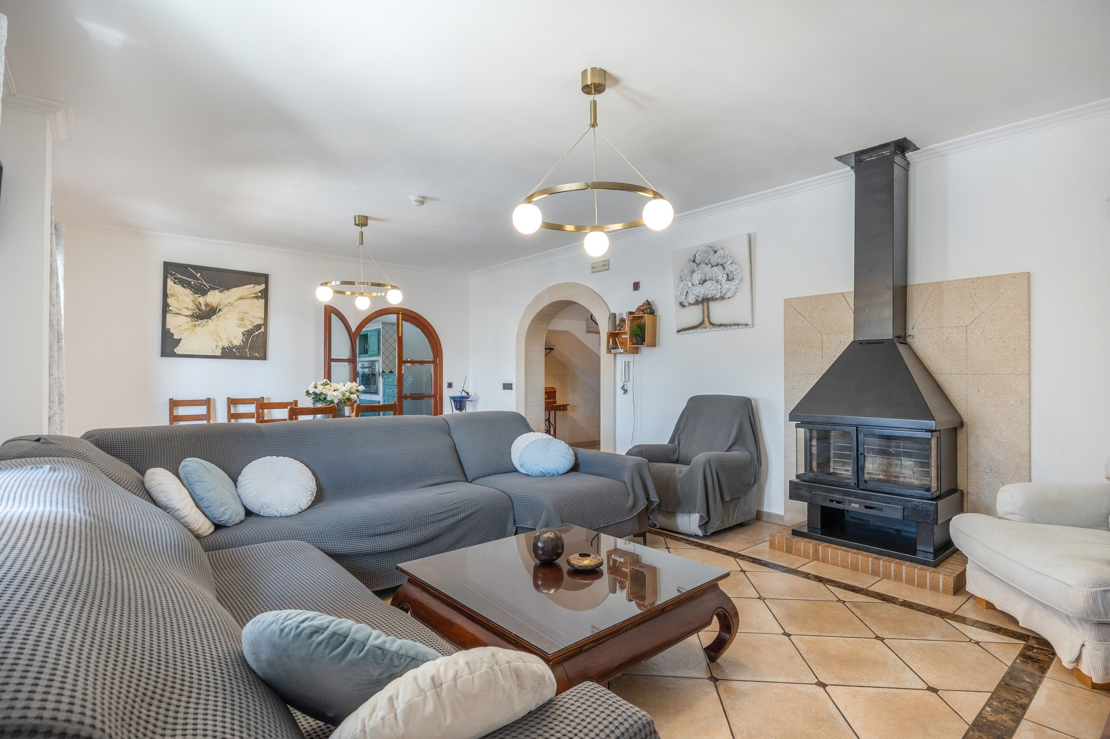 A living room with a sectional sofa, a coffee table, a fireplace, and a dining area with chairs and a table.