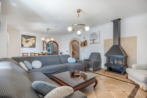 Een woonkamer met een hoekbank, een salontafel, een open haard, en een eetgedeelte met stoelen en een tafel.
