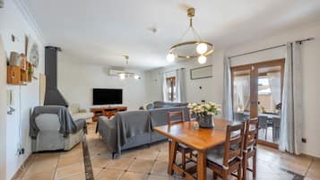 A living room with a sofa, TV, and a dining area with a table and chairs.