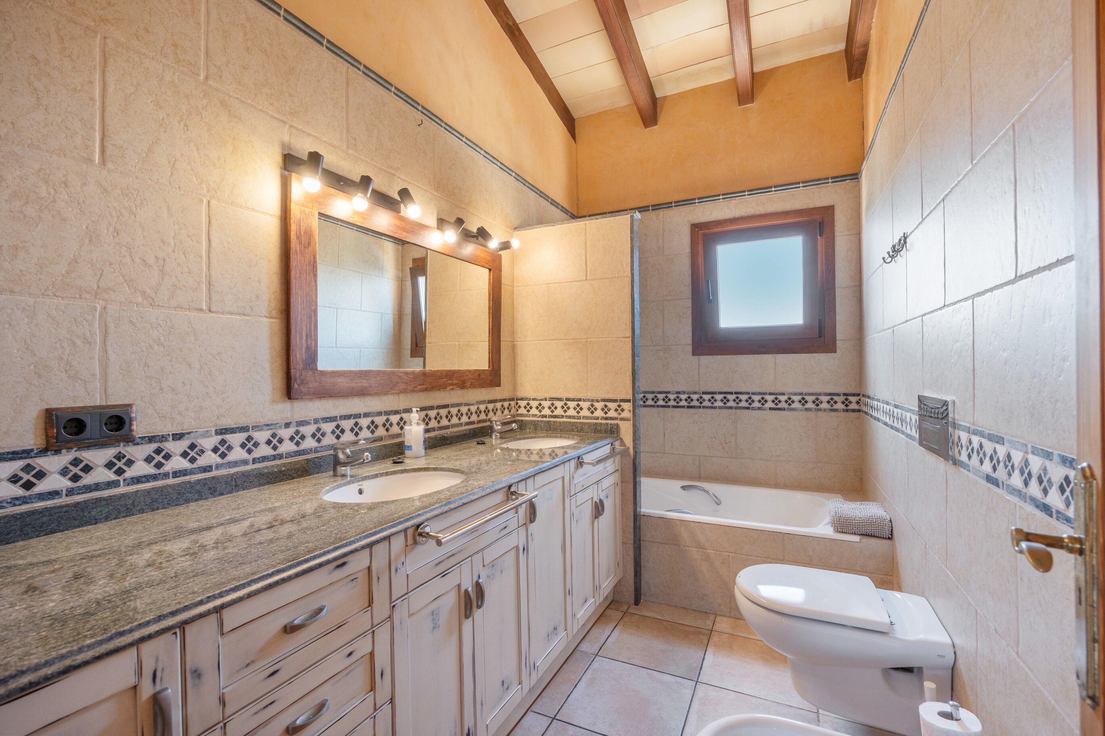 A bathroom with a double sink vanity, a toilet, and a bathtub.