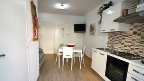 Une cuisine compacte avec des meubles blancs, une cuisinière à gaz, un four à micro-ondes et un coin repas comprenant une table et des chaises.