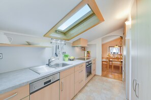 Una cocina moderna con tragaluz, lavavajillas integrado y comedor con mobiliario de madera.