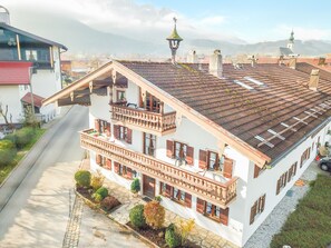 Un chalet traditionnel doté d’un toit à pente, de plusieurs balcons et d’un chemin de pierre menant à l’entrée.