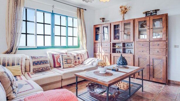 Een woonkamer met een bank, salontafel, kast en raam met gordijnen.