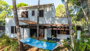 Une maison à deux étages dotée d’un hamac, d’un espace salon extérieur et d’une pergola.