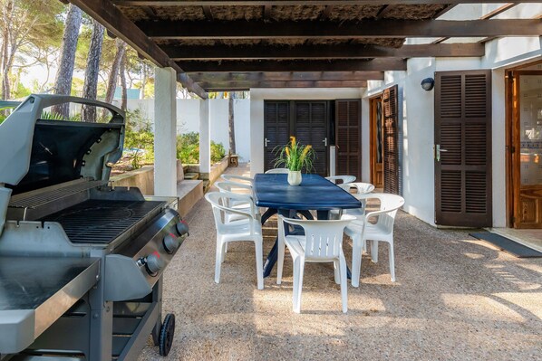 An outdoor patio with a grill, white plastic chairs, and a table. - Spacious Villa “Casa de Cala Gat” with Sea View, Mountain View, Wi-Fi, Garden & Terrace; Parking Available (Cala Rajada,)