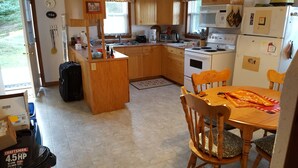 Una cocina compacta con armarios de madera, una mesa de comedor y un refrigerador.