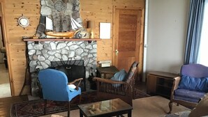 Un salón acogedor con chimenea de piedra, paredes de madera y asientos cómodos.