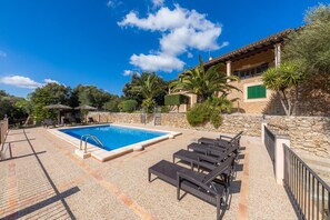 A pool area with lounge chairs, a stone wall, and a building with a tiled roof. - Fantastic Country House "Taconera" with Wi-Fi, Pool, Garden and Terraces (Artá)