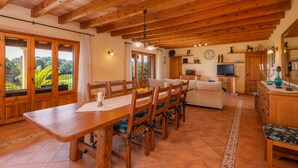 Un comedor con mobiliario de madera, un televisor y una cocina con armarios de madera.