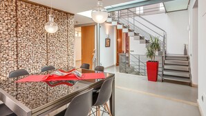 Een moderne eetruimte met een stenen muur, een glazen trap en een rode plantenbak.