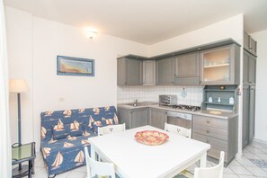 Una cucina funzionale con tavolo e sedie, un divano e una piccola isola con un fornello.