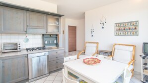 A kitchen with a stove, dishwasher, and a dining area with chairs and a table.