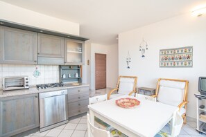 Una cucina con piano cottura, lavastoviglie e zona pranzo con sedie e tavolo.