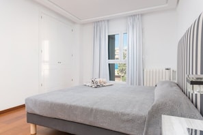 Une chambre à coucher avec un lit, une fenêtre avec des rideaux, un radiateur et une armoire.