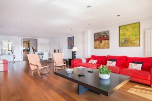 Un salon spacieux avec un canapé rouge, une table basse en bois et un fauteuil à rayures.