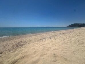 Une plage de sable fin, avec une eau d’un bleu limpide et une montagne qui se dessine à l’horizon.