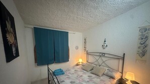 Une chambre à coucher avec un lit, une table de chevet, une horloge murale et une fenêtre avec des rideaux.