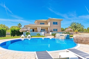 Une maison moderne dotée d’une piscine, de mobilier d’extérieur et d’un jardin bien entretenu.